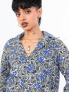 Person wearing a black and blue patterned shirt with a plain background