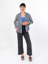 Woman wearing a patterned Shirt and black pants on a white background