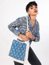 Person wearing a patterned shirt holding a blue and white bag with 'CHORAS' branding.