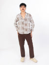 Person wearing a brown patterned shirt and brown pants on a white background