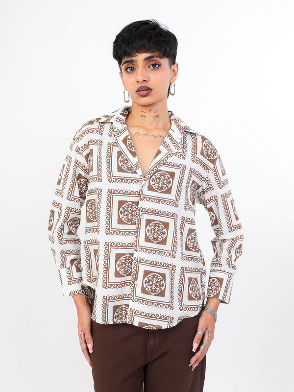 Woman wearing brown patterned shirt with a plain background