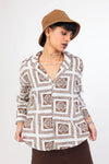 Woman wearing a brown patterned shirt and brown hat on a white background