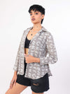 Person wearing a patterned shirt over a black top and shorts on a white background