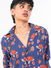 Women wearing a blue floral shirt with red flowers on a white background