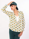 Woman wearing a Sun & Leaf shirt with green pants and cap on a white background