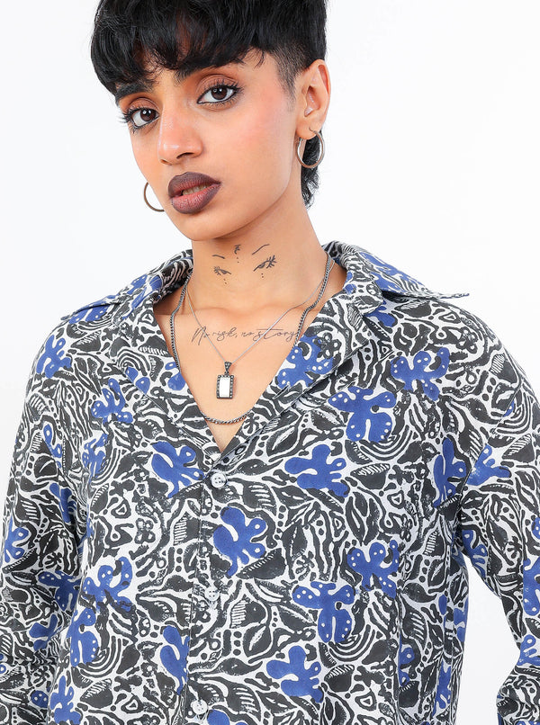 Person wearing a black and blue patterned shirt with a plain background