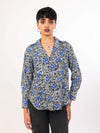 Woman wearing a patterned Shirt and black pants on a white background