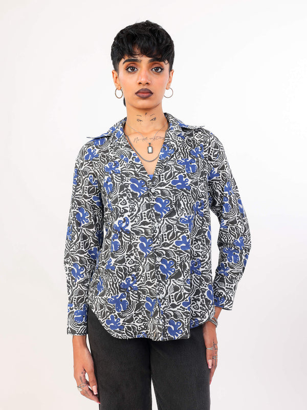 Woman wearing a patterned Shirt and black pants on a white background