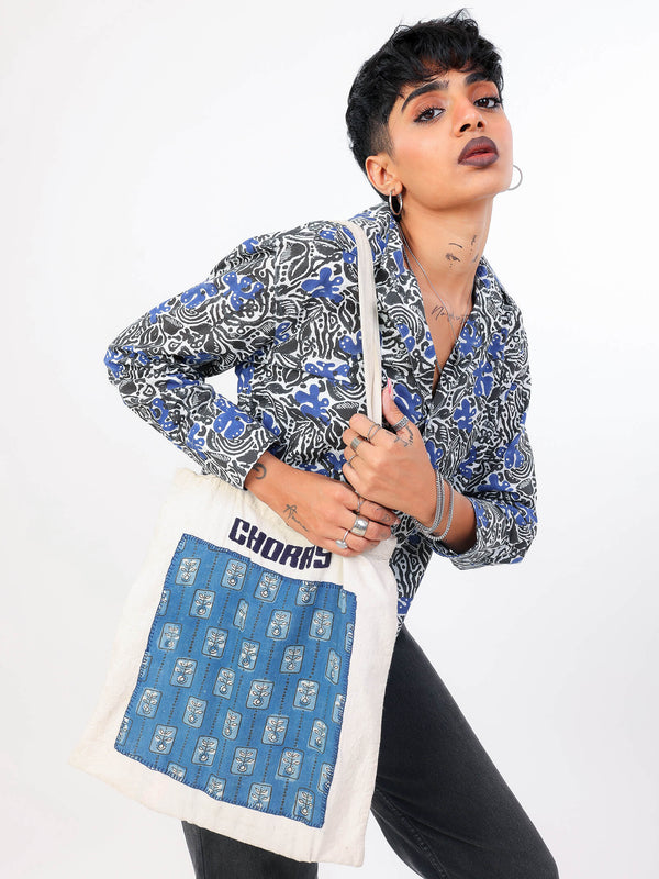 Person wearing a patterned shirt holding a blue and white bag with 'CHORAS' branding.