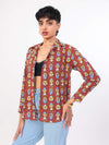 Woman wearing a patterned shirt over a black top and light blue jeans on a white background