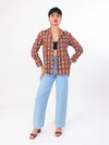 Woman wearing a patterned shirt and light blue jeans on a white background