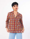 Person wearing a patterned red shirt with a plain background