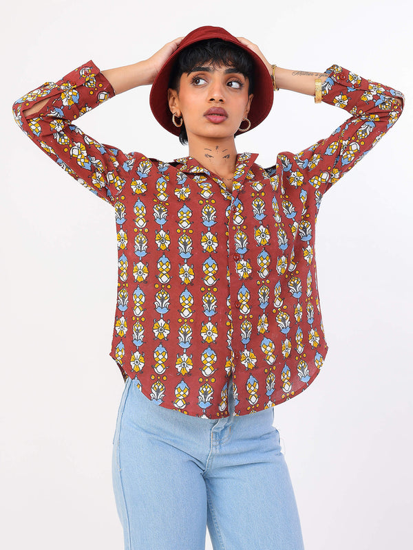 Person wearing a patterned red shirt and light blue jeans on a white background