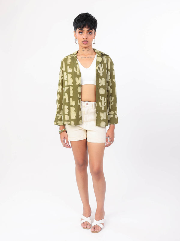 Woman wearing a green patterned shirt and white shorts on a white background