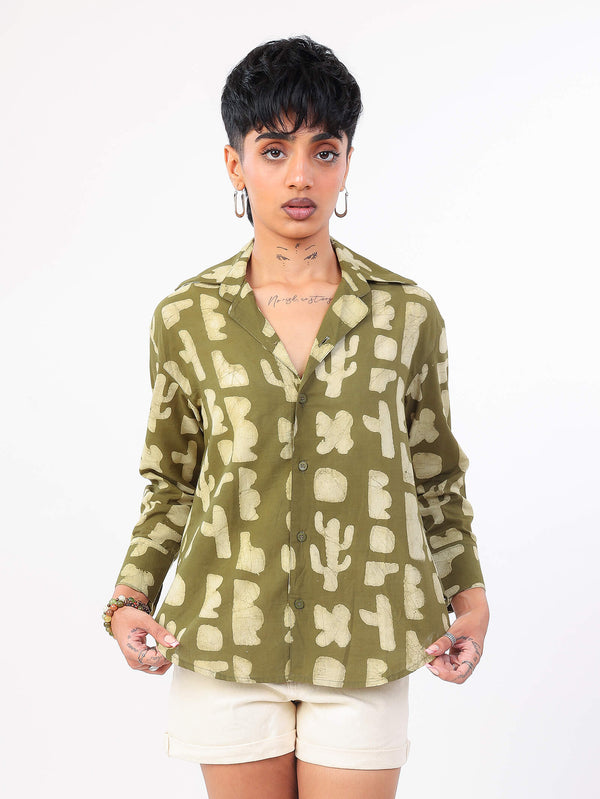 Woman wearing a green patterned shirt with white shorts on a white background
