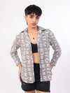 Person wearing a patterned shirt over a black top and shorts on a white background