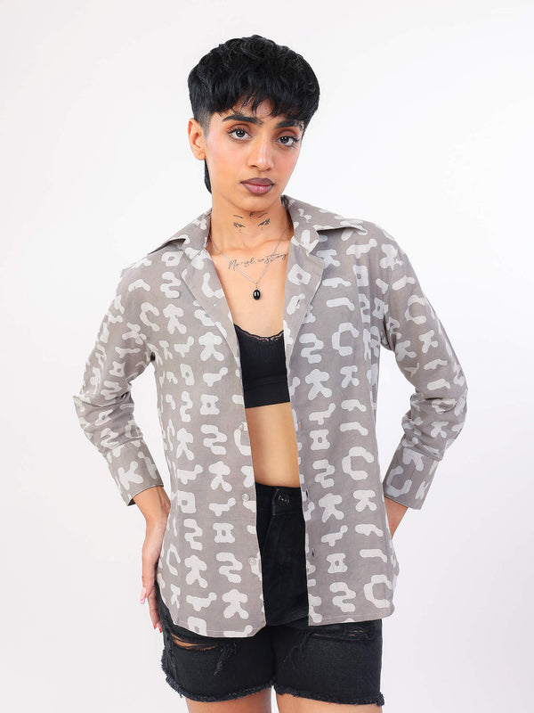 Person wearing a patterned shirt over a black top and shorts on a white background