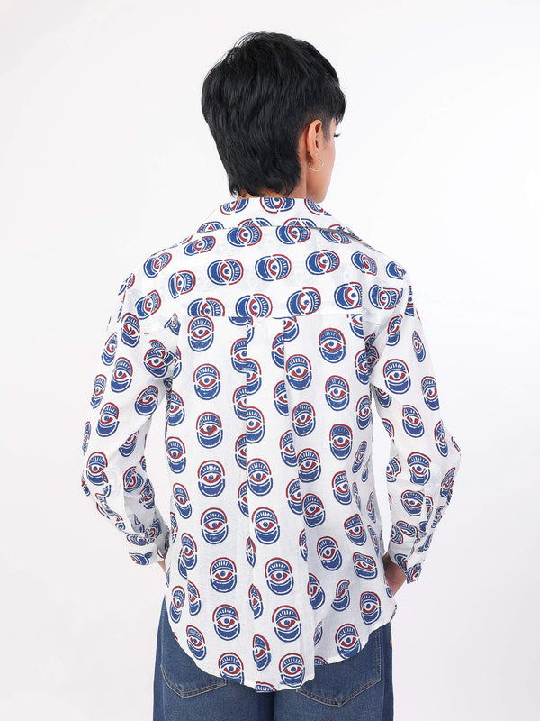 Women wearing a evil eye patterned shirt with blue jeans on a white background