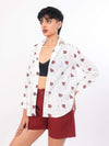 Woman wearing a white ocean print shirtand red shorts on a white background
