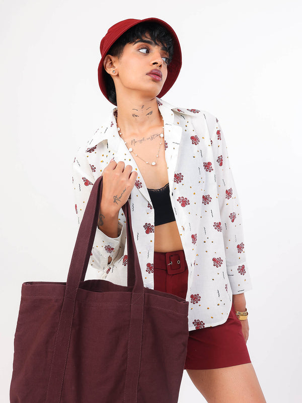 Woman wearing a white ocean print shirt, red shorts, and a red hat with a white background